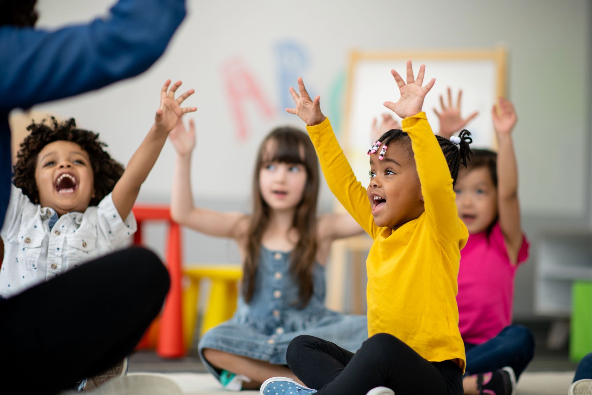 Smiling children reaching their arms up into the air.